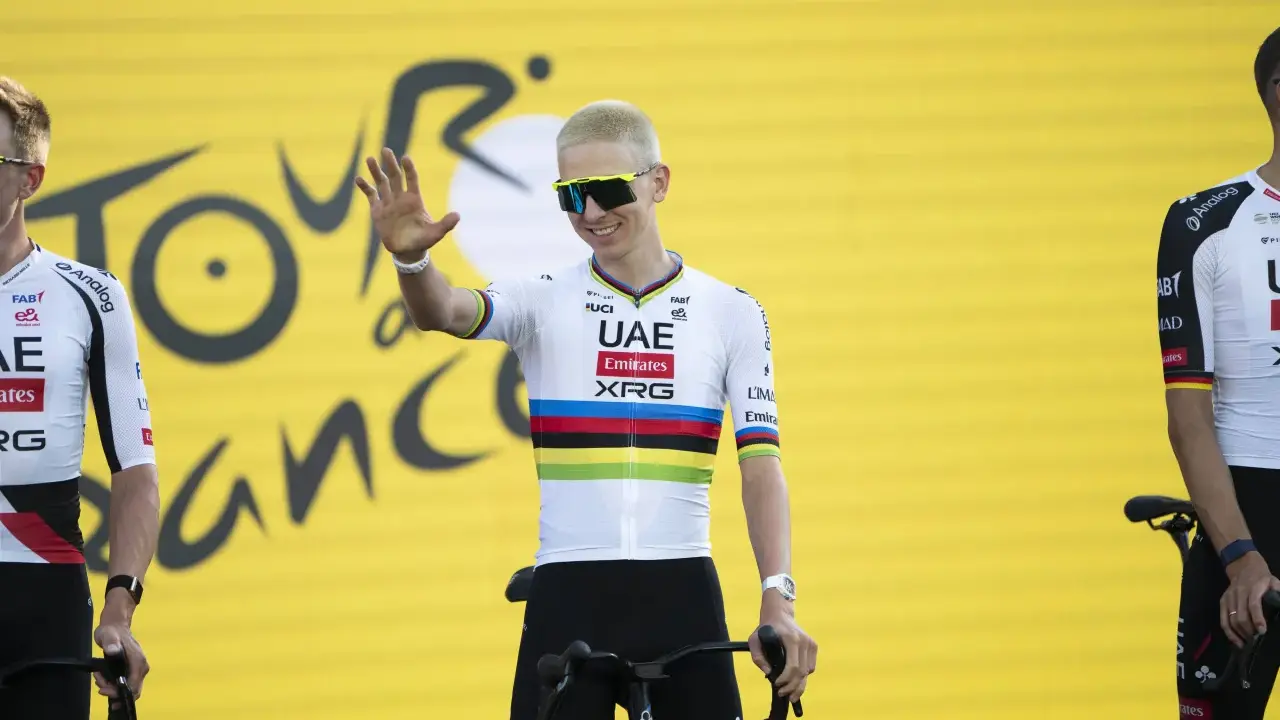 Radfahrer mit bunten Trikotfarben der Tour de France winkt fröhlich.