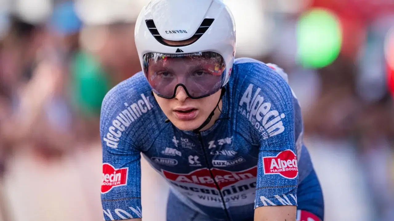 Juri Hollmann im Zeitfahr-Outfit, konzentriert auf der Strecke. Das blaue Trikot mit Alpecin-Logo und die aerodynamische Kopfbedeckung sind gut erkennbar.