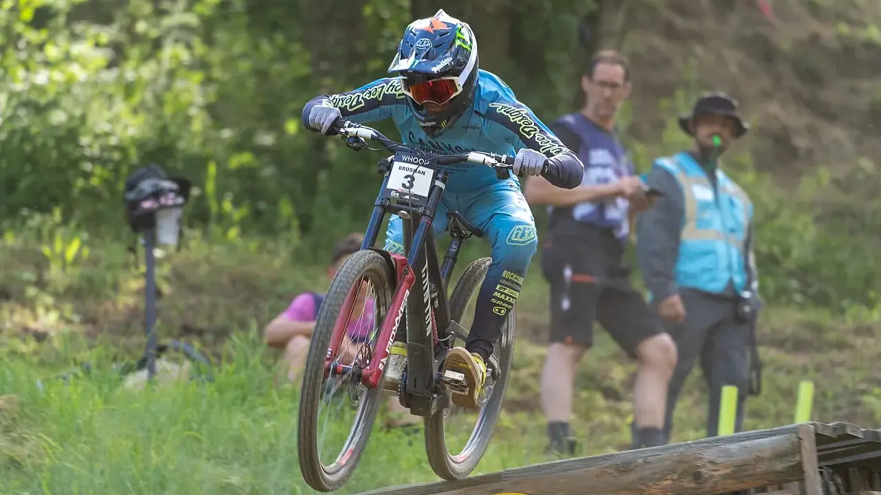 Troy Brosnan springt mit seinem Downhill-Bike über eine Holzrampe, bereit für den nächsten Sprung.