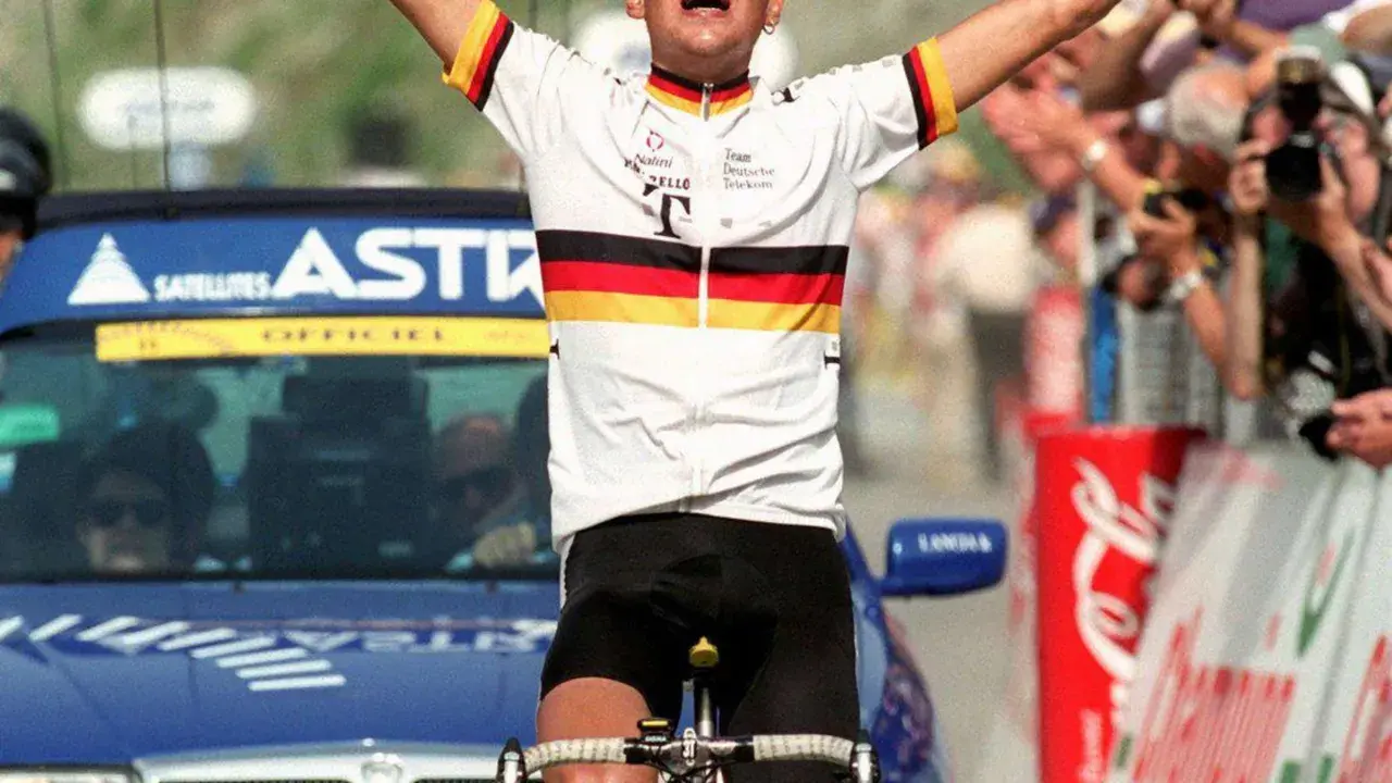 Jubelnder Radfahrer im Trikot des Teams Deutsche Telekom, ein deutscher Tour de France Sieger, mit erhobenen Armen vor jubelnder Menge.