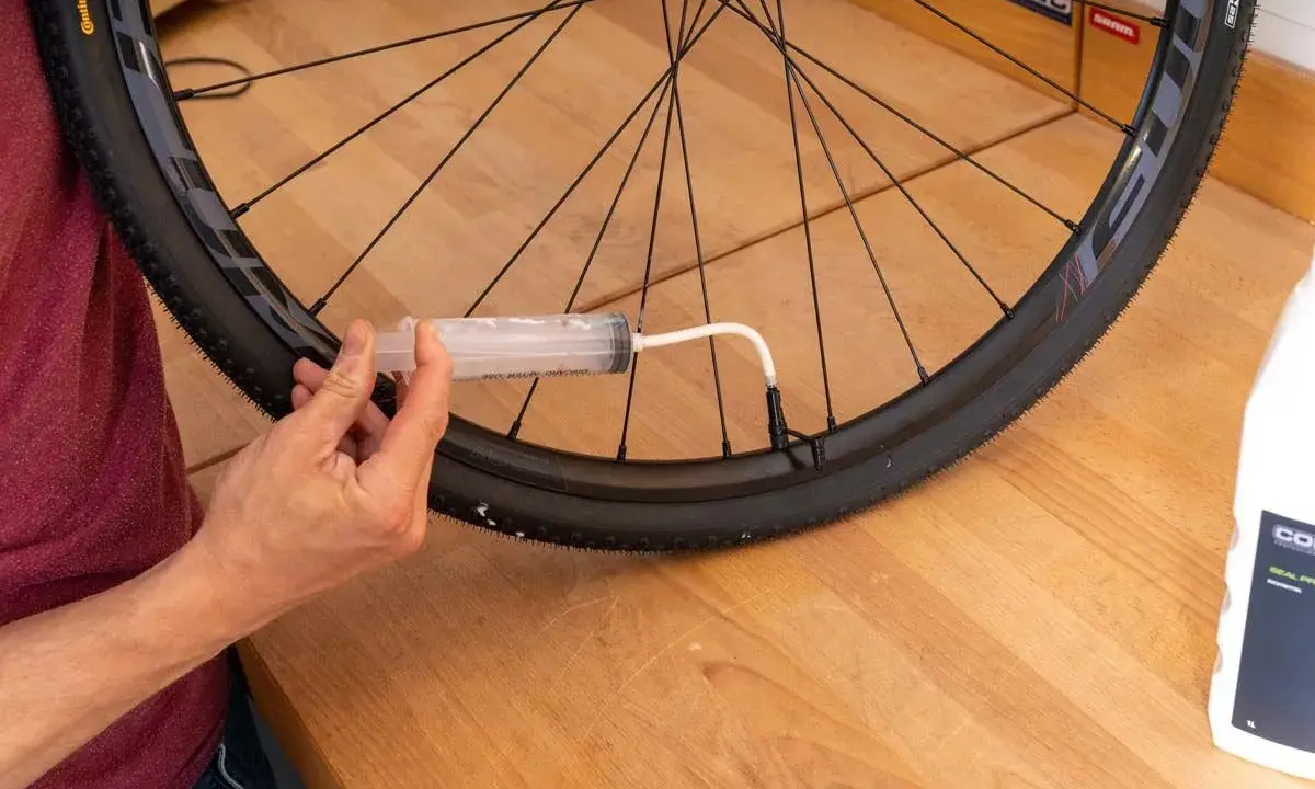 Mit einer Spritze wird Dichtmilch in den Tubeless Reifen gefüllt. So gelingt das tubeless reifen montieren.