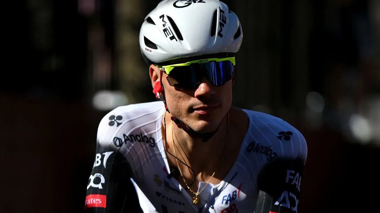 Juan Ayuso, Radsportler im weißen Trikot mit schwarzen Akzenten, trägt einen weißen Helm und eine gelbe Sportbrille.