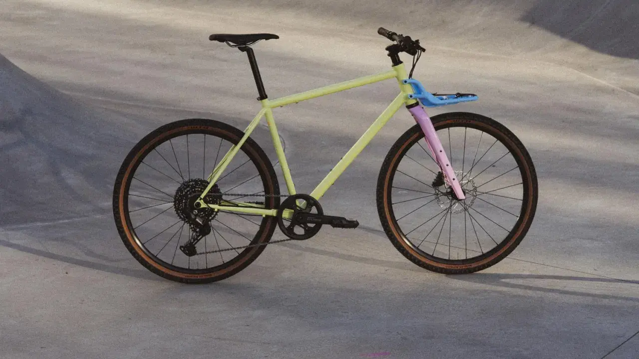 Ein gelbes Fahrrad mit rosa Gabel und blauem Gepäckträger, bereit für eine Fahrt durch die Stadt. Rose black lava 2 test.
