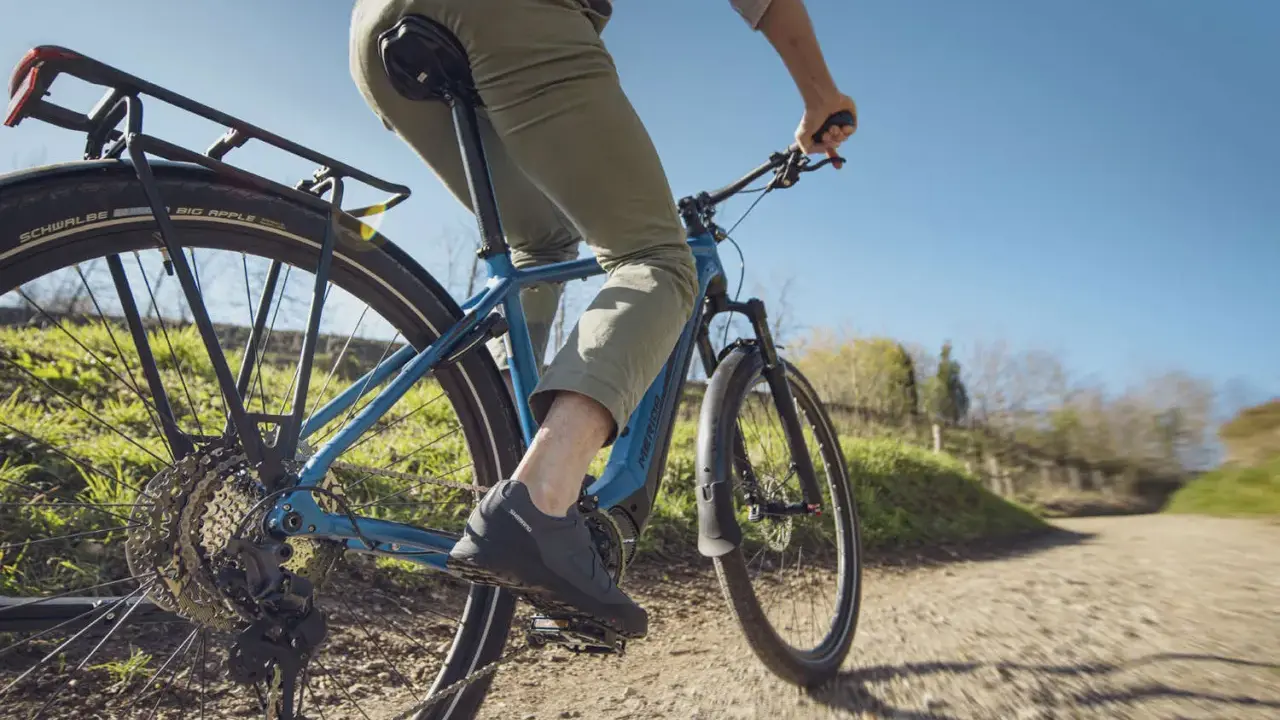 Fahrer auf einem blauen E-Bike mit Shimano Linkglide Schaltung genießt eine Fahrt auf einem Feldweg.