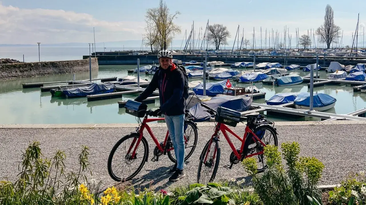 Mann mit Rennrad am Bodensee, bereit für die Bodensee Umrundung. Boote im Hafen.