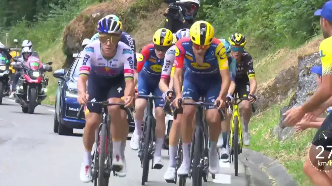 Radsportler im Peloton, darunter Cian Uijtdebroeks, kämpfen sich bergauf. Motorräder und ein Auto begleiten das Rennen.
