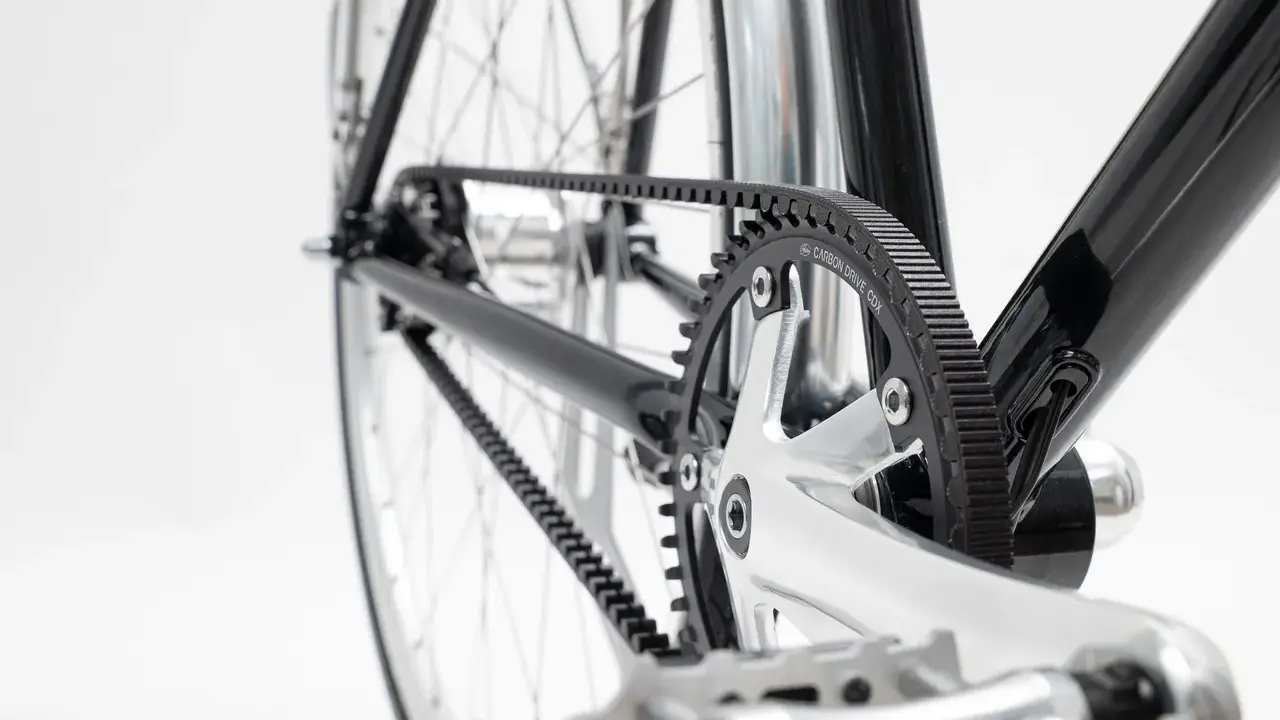 Nahaufnahme des Fahrradrahmens mit einem glänzenden Carbon Drive Riemenantrieb, der über Zahnräder läuft.