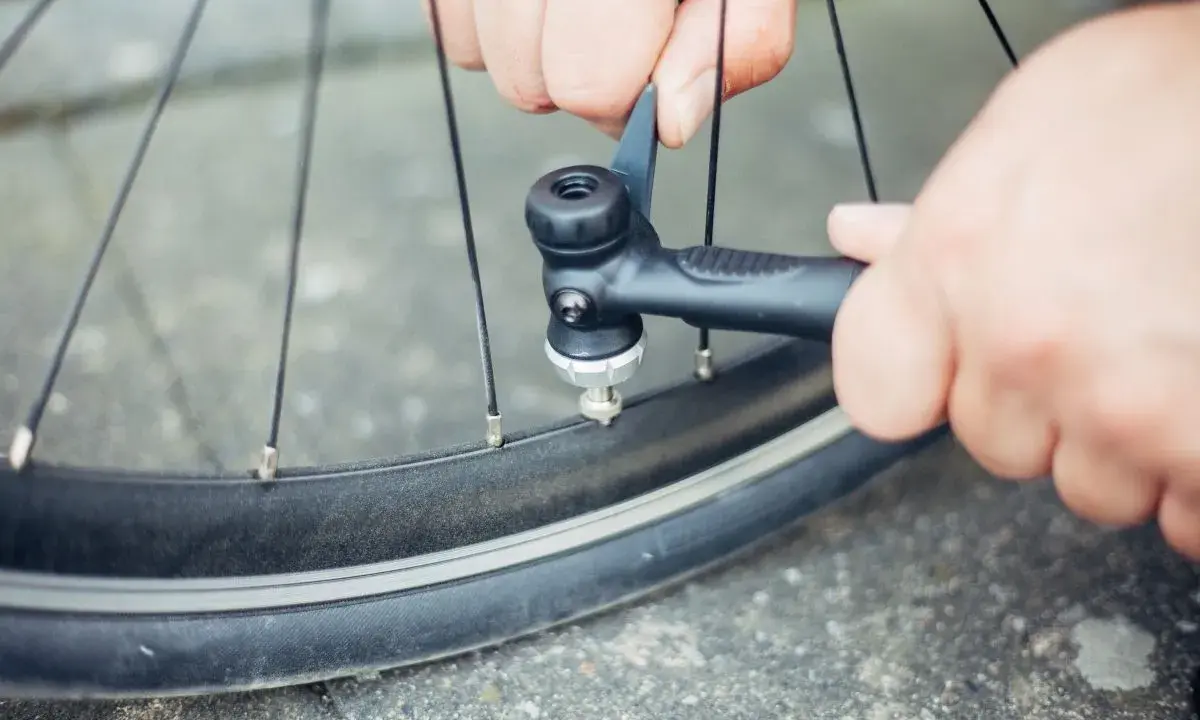 Hände pumpen mit einer Handpumpe Luft in ein Fahrradventil.