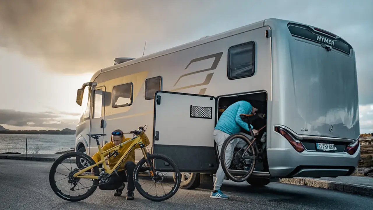 Zwei Personen laden Mountainbikes in einen Hymer Wohnwagen. Perfekt für Abenteuer mit dem e-bike wohnwagen.
