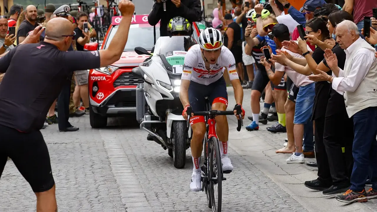 Giulio Ciccone fährt auf seinem Rennrad durch eine Gasse, umgeben von jubelnden Zuschauern und Motorrädern.