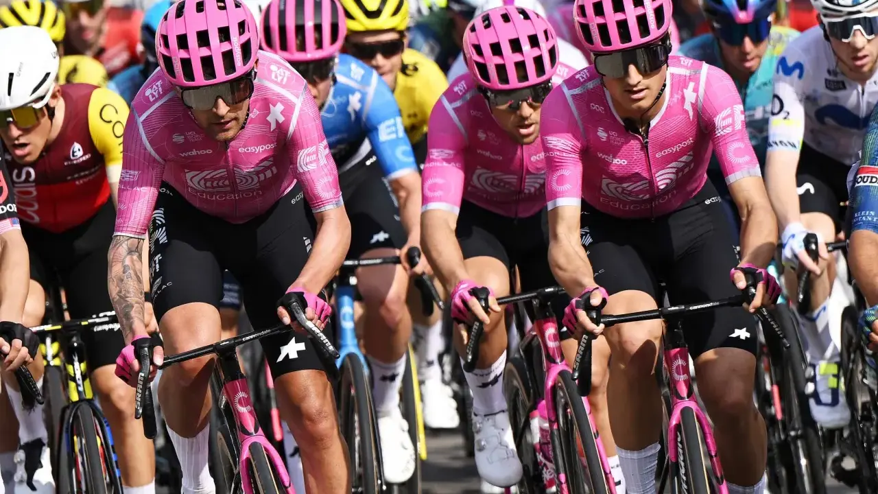 Radfahrer im pinken Trikot mit "Education First Team" Aufdruck, konzentriert auf der Strecke.