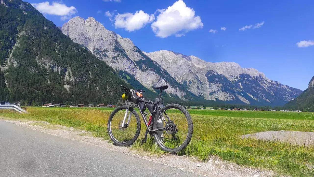 Rennrad für einen Alpencross, bereit für die Berge. Gepäcktaschen sind montiert, die Alpenkulisse ist atemberaubend.