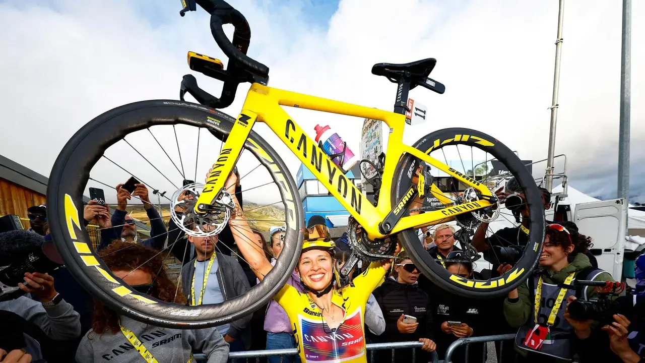 Jubelnde Radfahrerin hebt ihr gelbes Canyon-Rennrad hoch. Ein Moment des Triumphs bei der Frauen Tour de France.