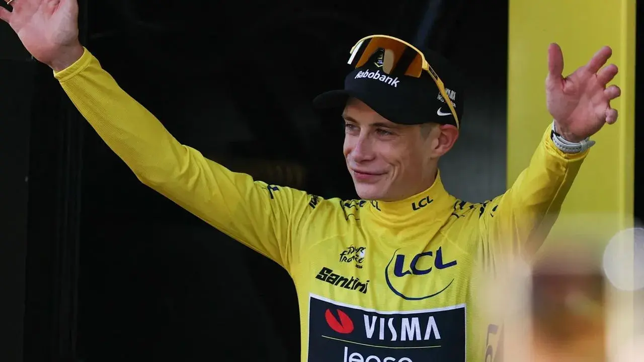 Radfahrer im gelben Trikot der Tour de France winkt jubelnd ins Publikum.
