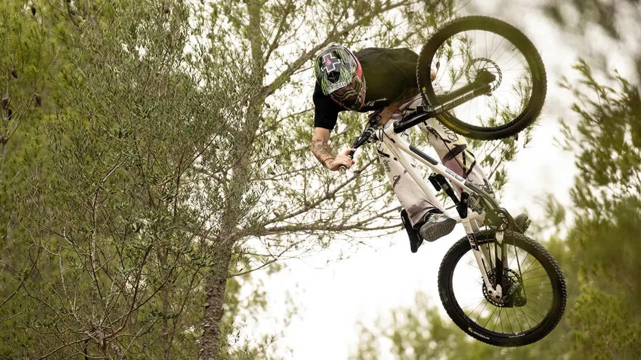 Tomas Lemoine fliegt mit seinem Mountainbike durch die Luft, umgeben von Bäumen.