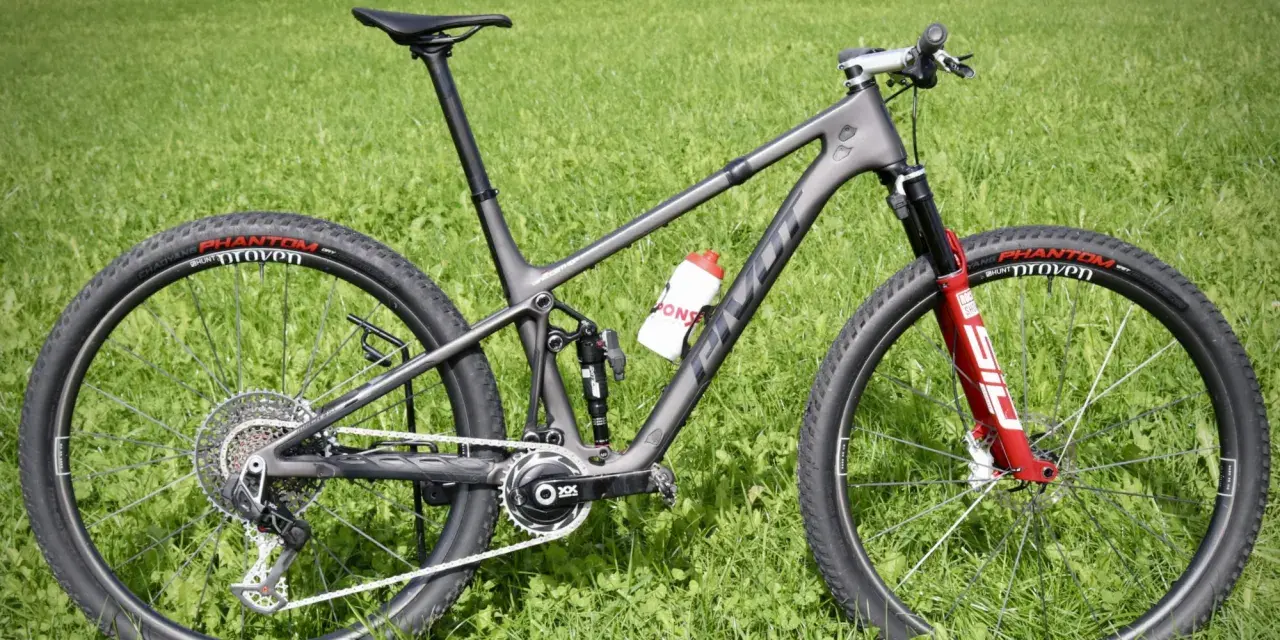 Ein graues Mountainbike mit roten Akzenten auf der Gabel und einer Trinkflasche. Die Reifen tragen die Aufschrift "Phantom Proven". Ein tolles Rad für die letzten Bikes der Saison.