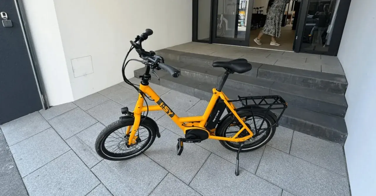 Gelbes i:SY E-Bike, das bei der Stiftung Warentest gut abgeschnitten hat, steht auf gepflastertem Untergrund vor einer Treppe.