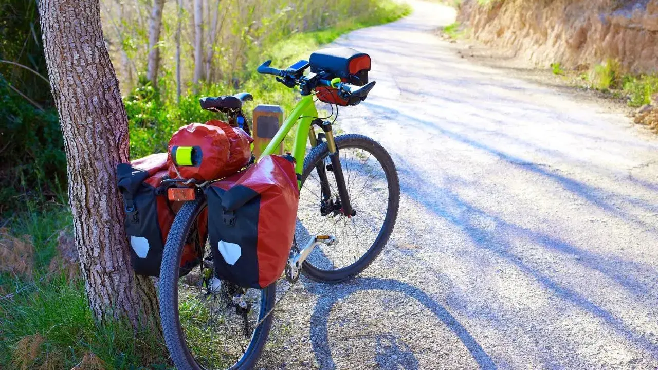 Ein grünes Trekkingrad mit roten Packtaschen steht am Wegesrand. Perfekt für Abenteuer, was ist ein Trekkingrad?