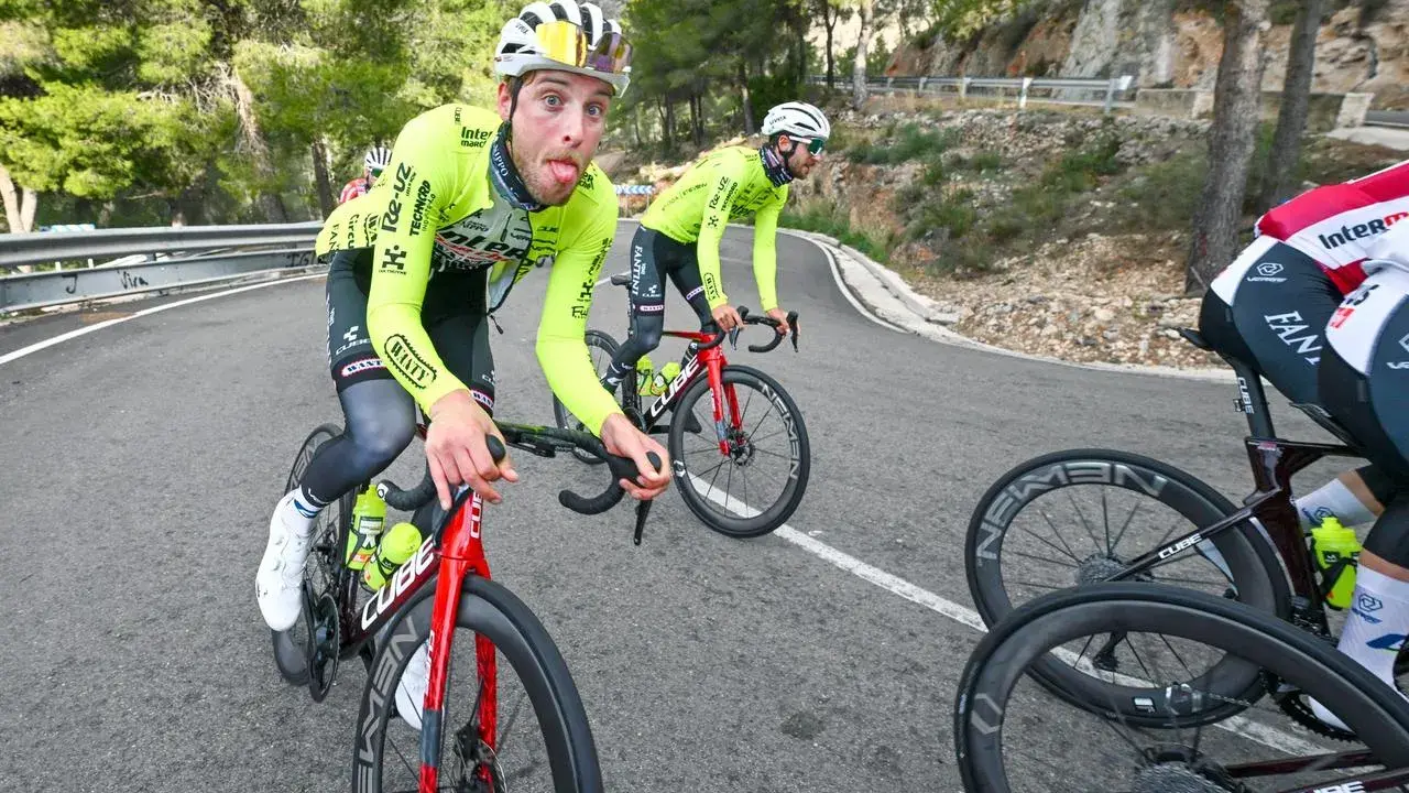 Jonas Rutsch zeigt Zunge auf dem Rennrad, während er auf einer kurvigen Bergstraße fährt.
