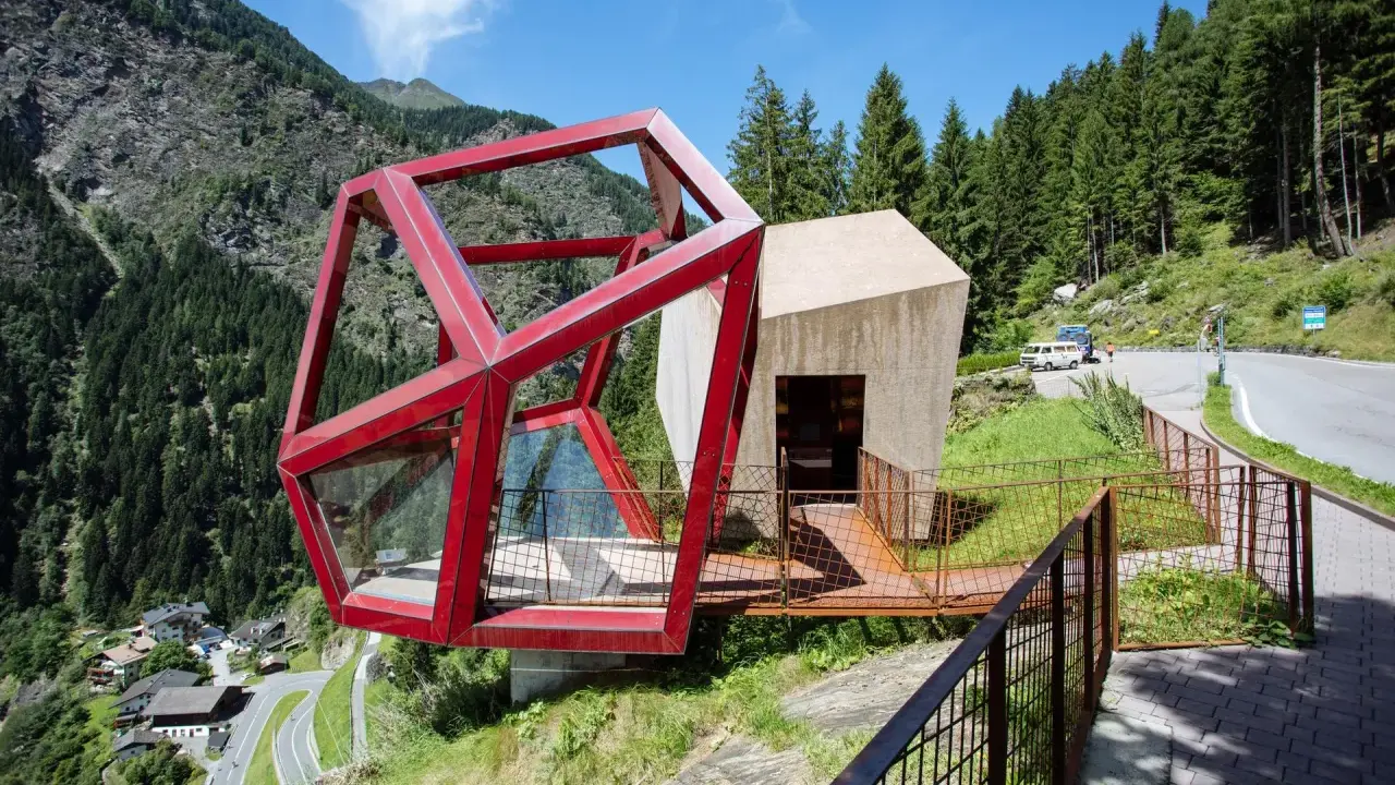 Moderne Architektur am Timmelsjoch. Ein Rennradfahrer genießt die Aussicht auf die Serpentinenstraße.
