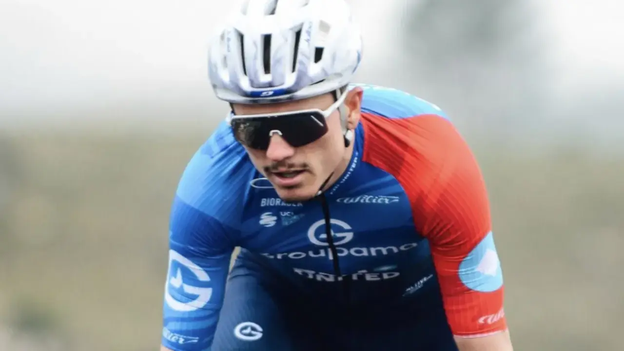 David Gaudu im blauen und roten Trikot, mit Helm und Sonnenbrille, konzentriert sich auf das Rennen.