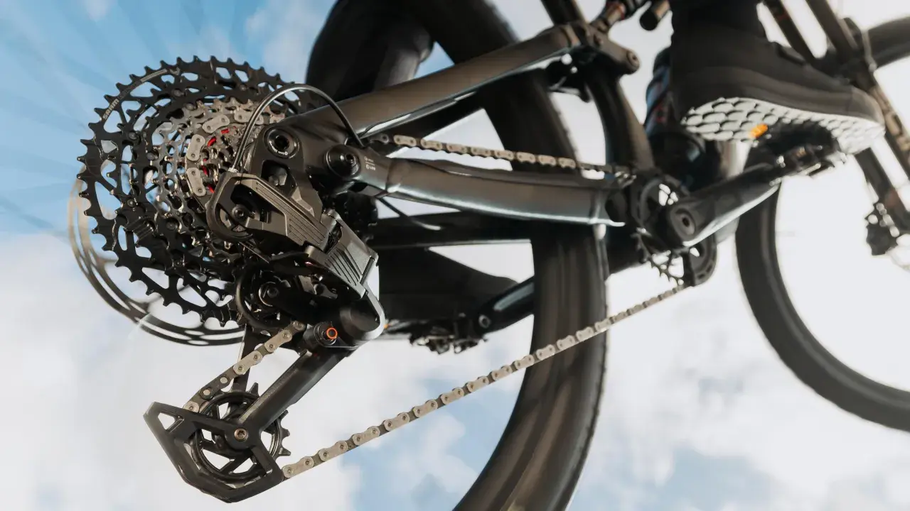 Nahaufnahme einer SRAM Schaltung am Fahrrad. Die Kette läuft über die Kassette, während ein Schuh auf dem Pedal zu sehen ist. Perfekt, um die SRAM Schaltung einzustellen.