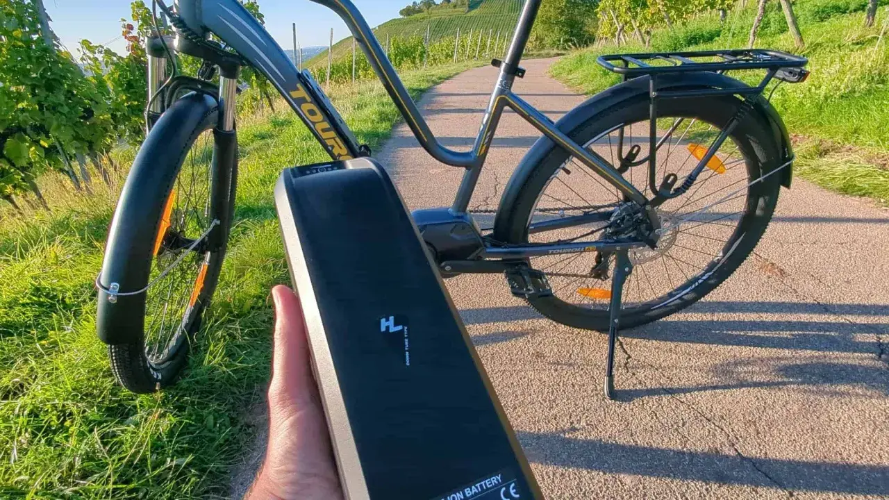 E-Bike Akku wird abgenommen, um das E-Bike zu reinigen. Die Sonne scheint auf die Weinberge.