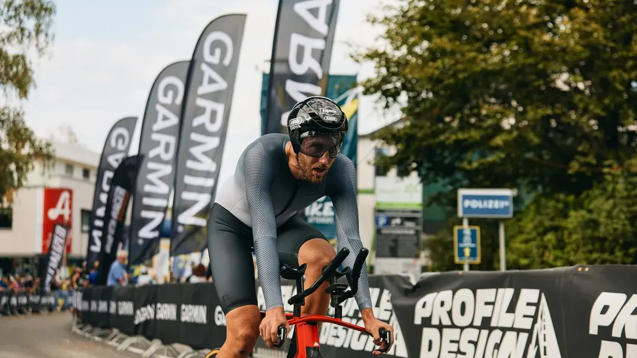 Fokus auf den Radfahrer beim rad wm zeitfahren. Er kämpft sich durch, die Garmin-Fahnen wehen im Hintergrund.