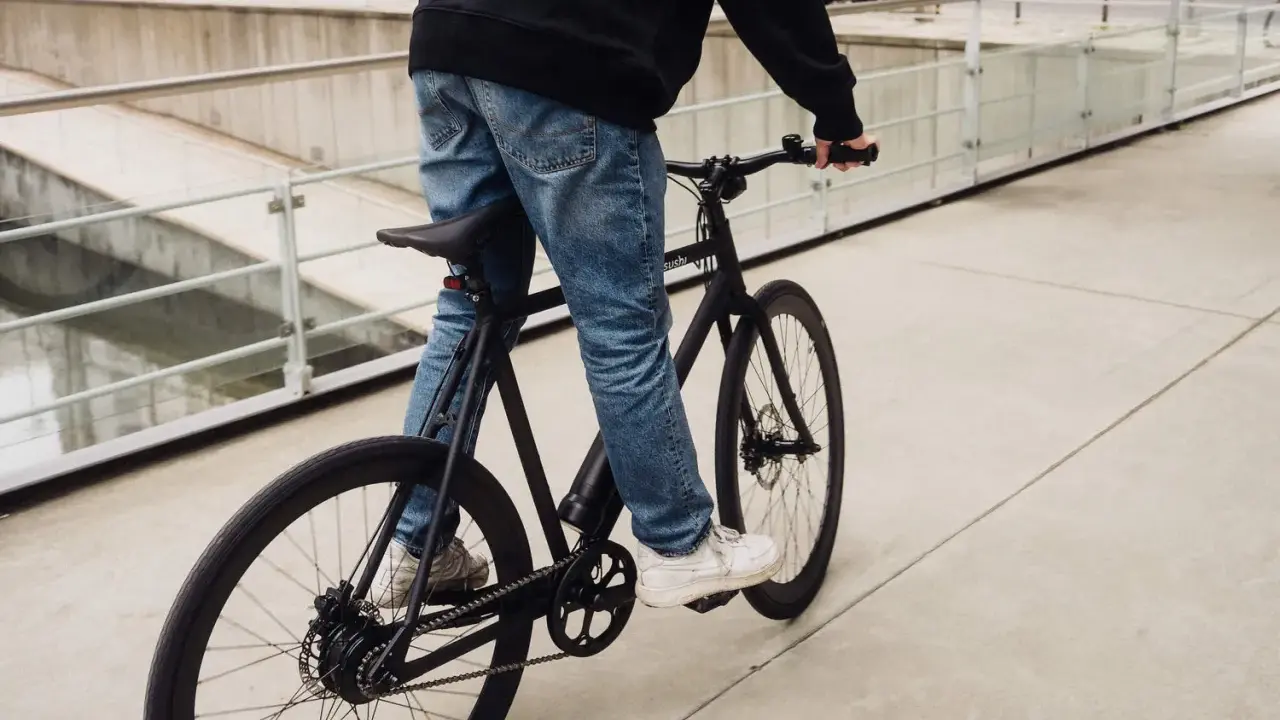 Ein Mann fährt ein schwarzes Fahrrad. Die Marke "sushi" ist auf dem Rahmen zu sehen. Die Nachricht "vanmoof insolvent" hallt nach.