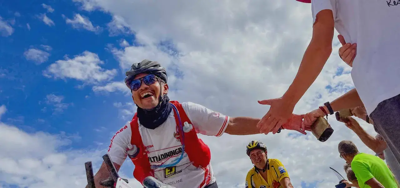 Glücklicher Radfahrer gibt High-Five während Paris Brest Paris. Ein weiterer Radfahrer im Hintergrund.