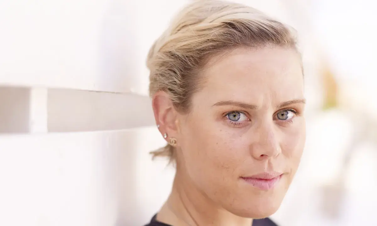 Nahaufnahme von Tiffany Cromwell mit blonden Haaren und blauen Augen, die nachdenklich in die Kamera blickt.
