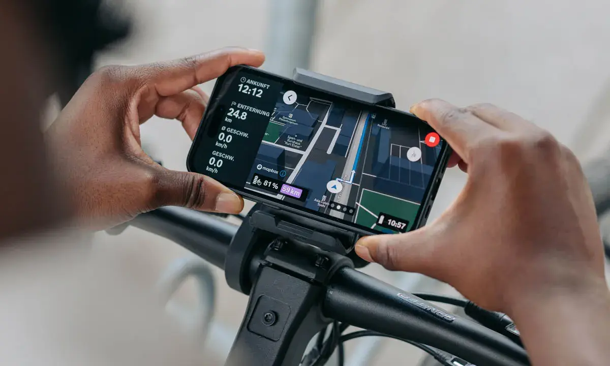 Hände halten Smartphone mit Bosch Flow App Navigation offline. Karte zeigt Route, Distanz und Geschwindigkeit.