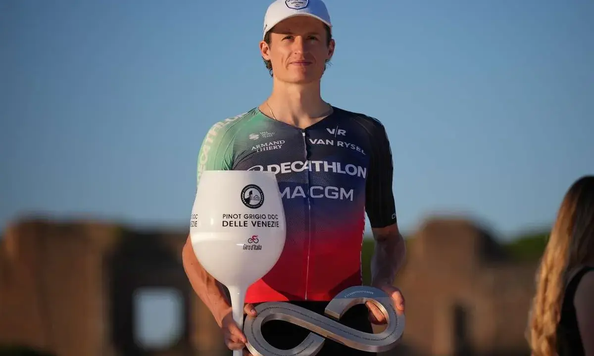 Felix Gall feiert seinen Sieg mit einem Pokal in Weinglasform und einer Infinity-Trophäe.