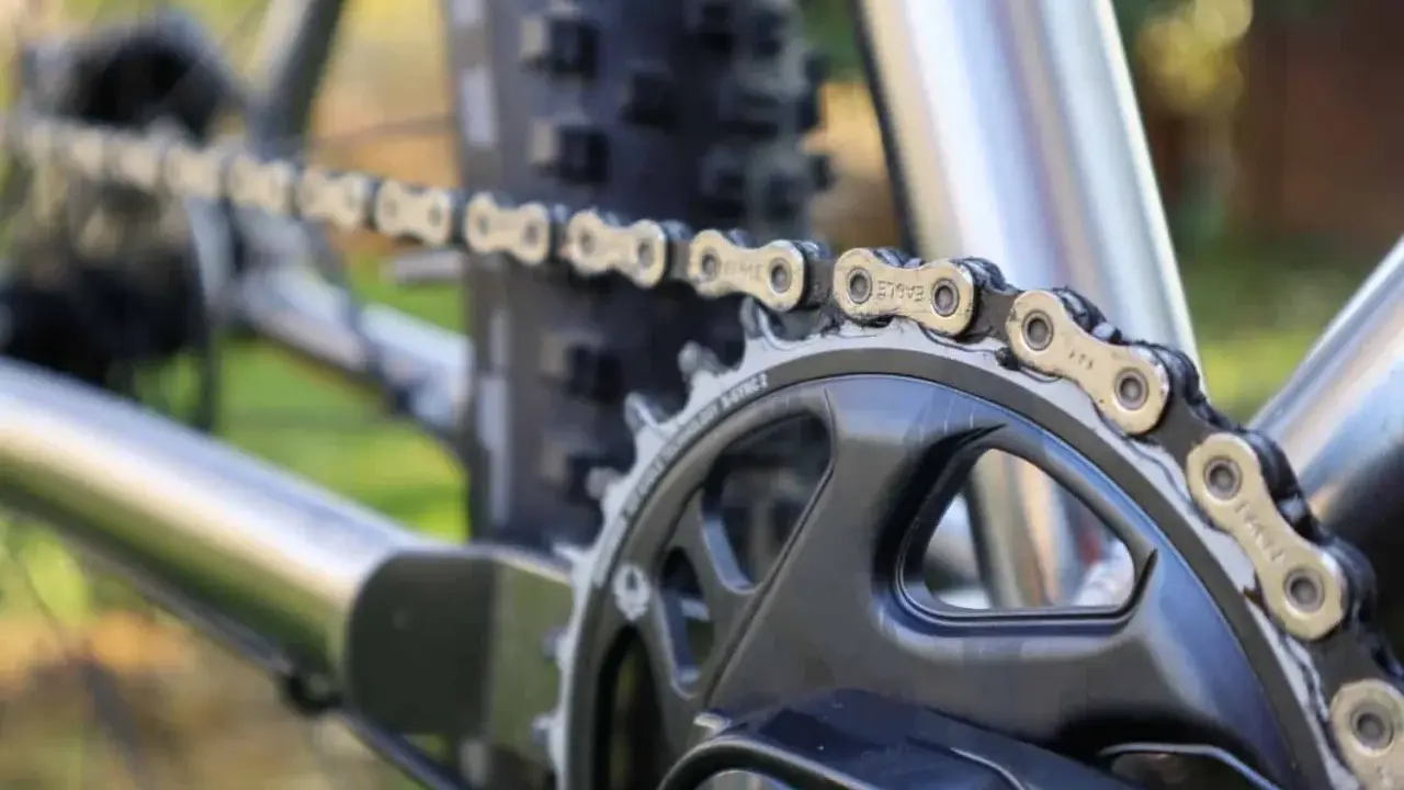 Nahaufnahme einer Fahrradkette, die über ein Kettenblatt läuft. Die Kette zeigt deutliche Gebrauchsspuren, was auf die Shimano Ketten Unterschiede in Bezug auf Haltbarkeit und Leistung hinweist.