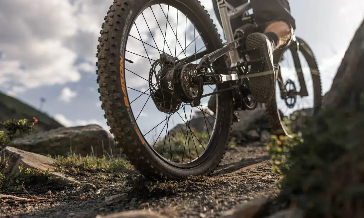 Detailaufnahme eines Mountainbikes mit 3x3 Schaltung auf steinigem Trail. Der breite Reifen meistert das Gelände.