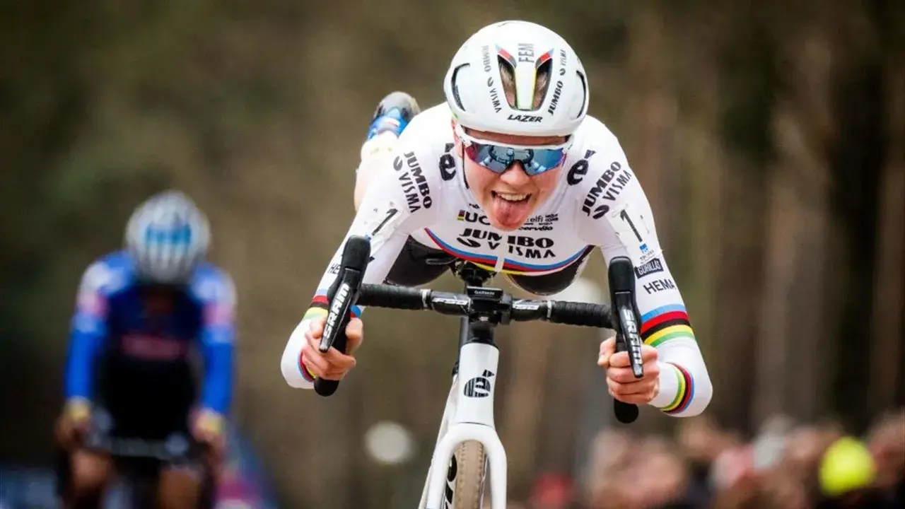 Fem van Empel zeigt Zunge beim Radrennen, trägt weißes Trikot mit Jumbo Visma Logo.