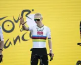 Radfahrer mit bunten Trikotfarben der Tour de France winkt fröhlich.