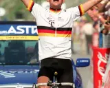 Jubelnder Radfahrer im Trikot des Teams Deutsche Telekom, ein deutscher Tour de France Sieger, mit erhobenen Armen vor jubelnder Menge.
