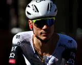 Juan Ayuso, Radsportler im weißen Trikot mit schwarzen Akzenten, trägt einen weißen Helm und eine gelbe Sportbrille.