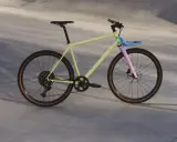 Ein gelbes Fahrrad mit rosa Gabel und blauem Gepäckträger, bereit für eine Fahrt durch die Stadt. Rose black lava 2 test.