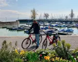 Mann mit Rennrad am Bodensee, bereit für die Bodensee Umrundung. Boote im Hafen.