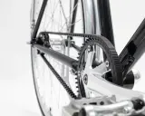 Nahaufnahme des Fahrradrahmens mit einem glänzenden Carbon Drive Riemenantrieb, der über Zahnräder läuft.
