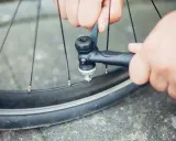 Hände pumpen mit einer Handpumpe Luft in ein Fahrradventil.