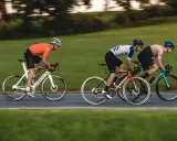 Drei Radfahrer auf schnellen Rennrädern, die an die Tour de France erinnern, fahren auf einer Straße.