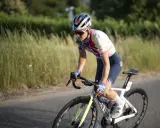Elise Chabbey in voller Fahrt auf ihrem Rennrad, die Konzentration im Blick, während sie durch eine grüne Landschaft fährt.