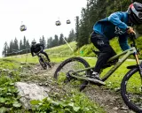Zwei Mountainbiker auf einem steilen Trail, Seilbahnen im Hintergrund. Einer fährt ein Rad mit Mullet-Setup, was ist ein Mullet?