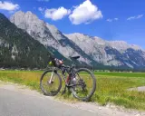 Rennrad für einen Alpencross, bereit für die Berge. Gepäcktaschen sind montiert, die Alpenkulisse ist atemberaubend.