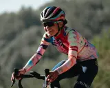 Ricarda Bauernfeind lacht auf ihrem Rennrad, trägt einen bunten Helm und ein auffälliges Trikot mit geometrischen Mustern.