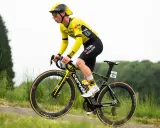 Matthew Brennan im gelben Trikot fährt auf seinem Rennrad durch eine grüne Landschaft.