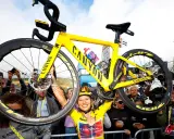 Jubelnde Radfahrerin hebt ihr gelbes Canyon-Rennrad hoch. Ein Moment des Triumphs bei der Frauen Tour de France.